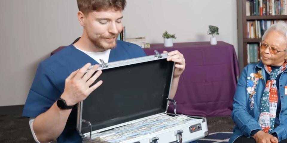 MrBeast opens a briefcase full of cash as a woman to his right looks on.