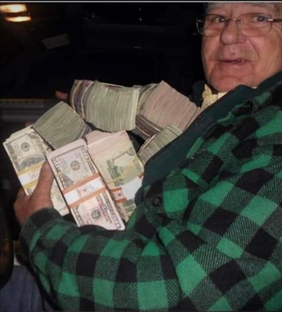 In a photo provided by the commissioner of Maine's Department of Marine Resources, a buyer poses with cash used to purchase elvers. The photo was taken before Maine eliminated the use of cash in the fishery. 