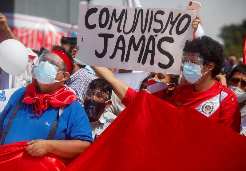 FOTO DE ARCHIVO: Personas sostienen un cartel que dice "Comunismo nunca" durante una protesta, encabezada por el ex candidato presidencial Rafael López Aliaga (que no está en la foto), contra el candidato socialista Pedro Castillo, quien se enfrentará a la opositora de derecha Keiko Fujimori en una segunda vuelta el 6 de junio, en Lima, Perú, el 8 de mayo de 2021.