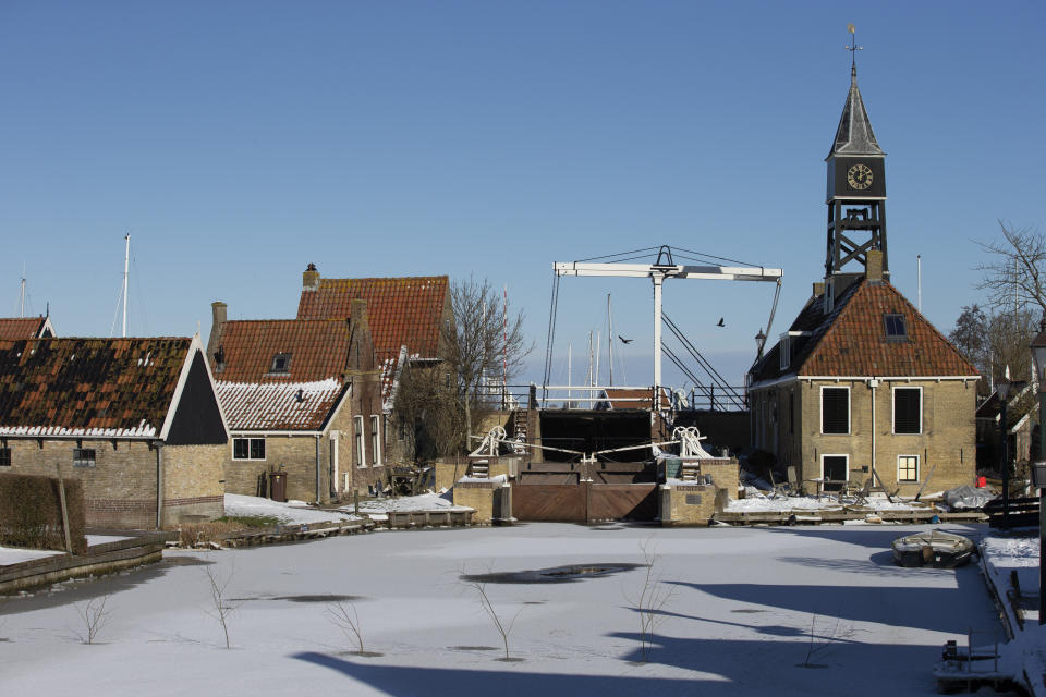 Ice covers a canal in Hindeloopen, Netherlands, Thursday, Feb. 11, 2021. The deep freeze gripping parts of Europe served up fun and frustration with heavy snow cutting power to some 37,000 homes in central Slovakia. (AP Photo/Peter Dejong)