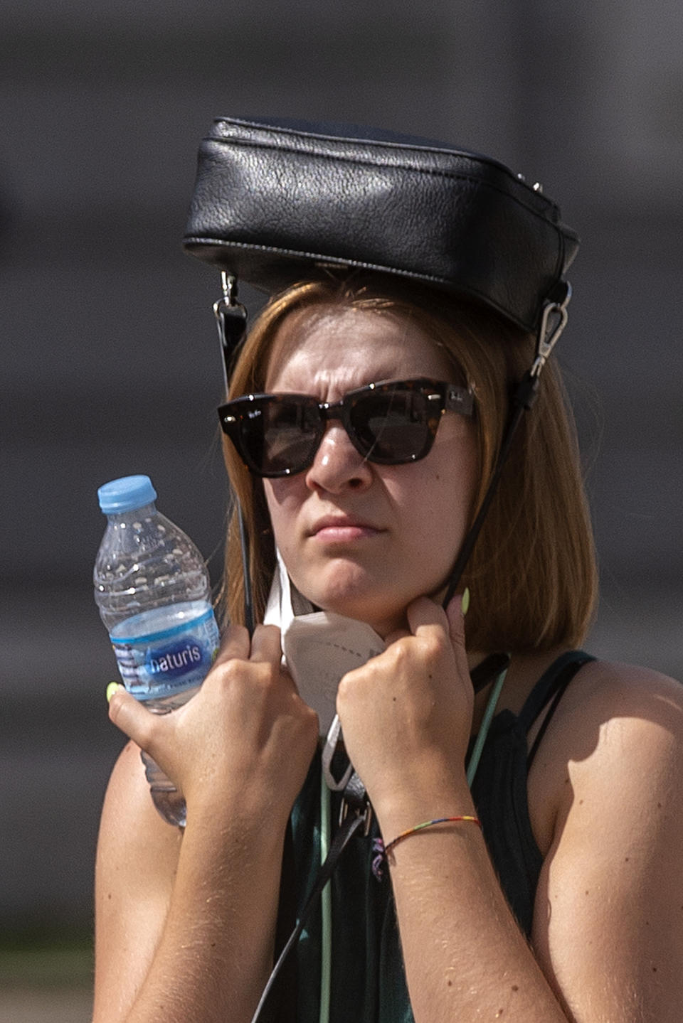 A woman tries to protect herself from the sun with her handbag on her head during a heatwave in Madrid, Spain, Friday, Aug. 13, 2021. Stifling heat is gripping much of Spain and Southern Europe, and forecasters say worse is expected to come. (AP Photo/Andrea Comas)