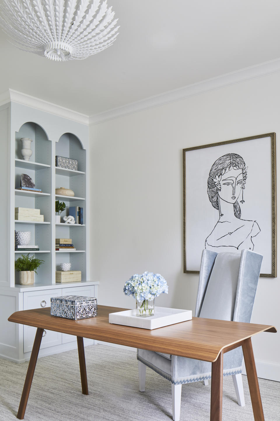 A white toned home office with a neat bookshelf on the side