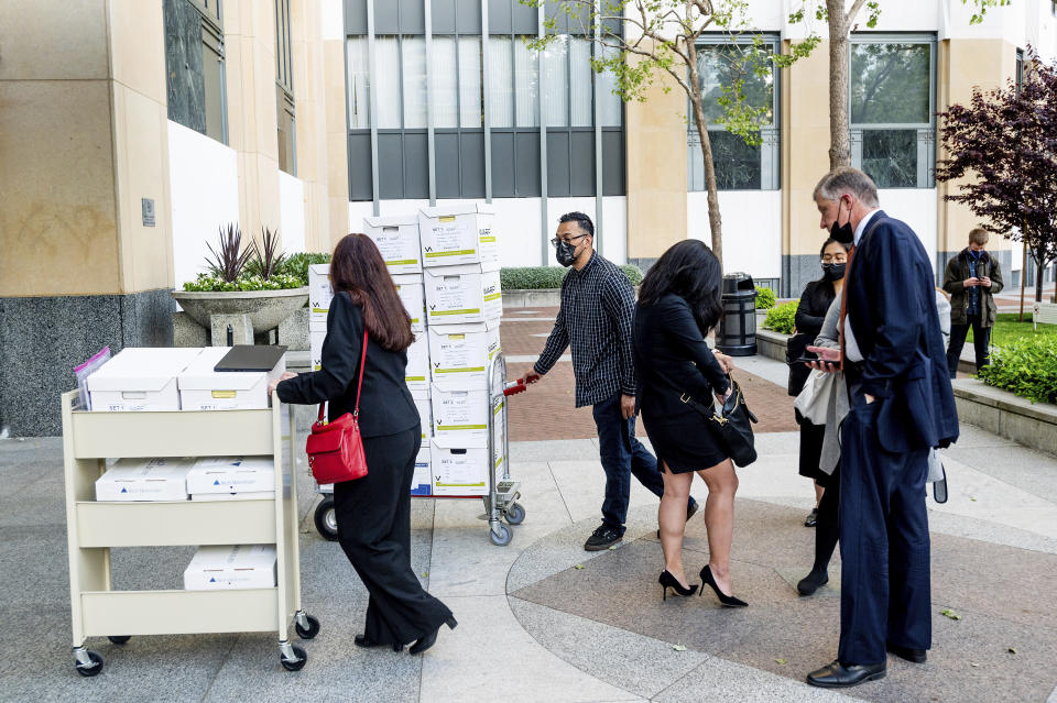 Members of Apple's legal team roll exhibit boxes into the Ronald V. Dellums building in Oakland, Calif., as the company faces off in federal court against Epic Games on Monday, May 3, 2021. Epic, maker of the video game Fortnite, charges that Apple has transformed its App Store into an illegal monopoly. (AP Photo/Noah Berger)