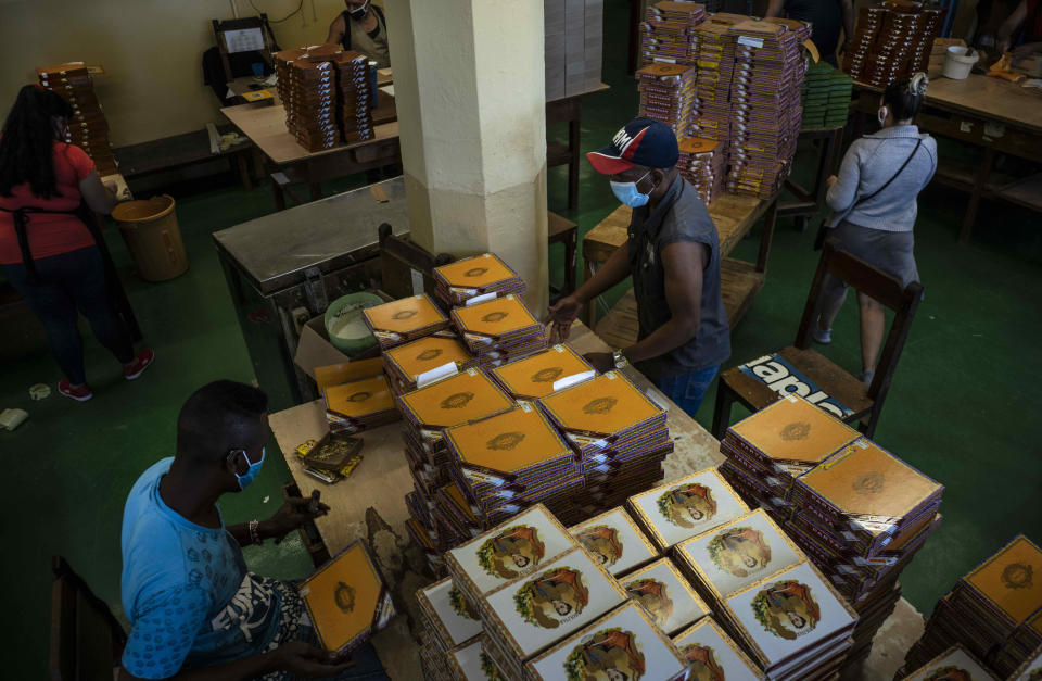 Trabajadores con máscaras protectoras preparan cajas llenas de puros en la fábrica de puros Partagás en La Habana, Cuba, el jueves 11 de marzo de 2021. (AP Foto/Ramón Espinosa)