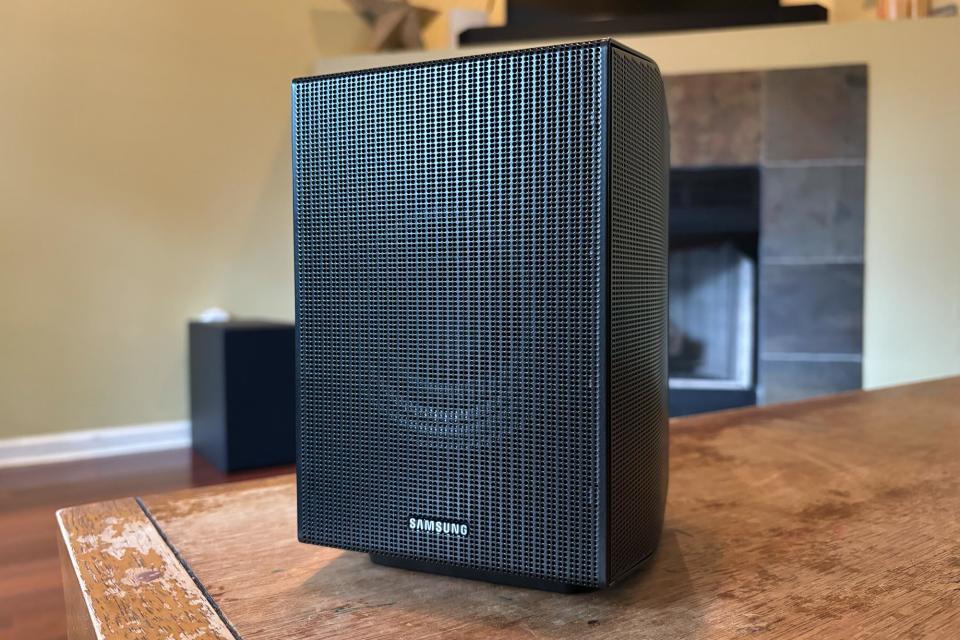 One of the Q990D's rear speakers rests on a wooden table. 