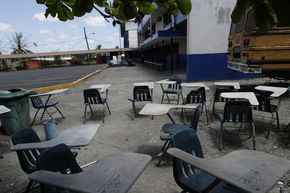Student desks sit in the shade next to the parking lot of the closed Francisco Beckman high school, where a professor who died of the coronavirus worked, on the outskirts of Panama City, Thursday, March 12, 2020, on the first day that schools closed nation-wide. The vast majority of people recover from the new virus. (AP Photo/Arnulfo Franco)