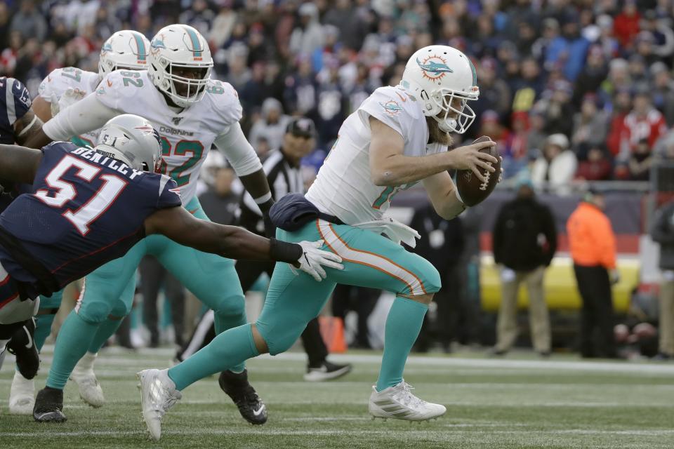 Miami Dolphins quarterback Ryan Fitzpatrick runs past New England Patriots linebacker Ja'Whaun Bentley, left, on the way to a touchdown in the second half of an NFL football game, Sunday, Dec. 29, 2019, in Foxborough, Mass. (AP Photo/Elise Amendola)