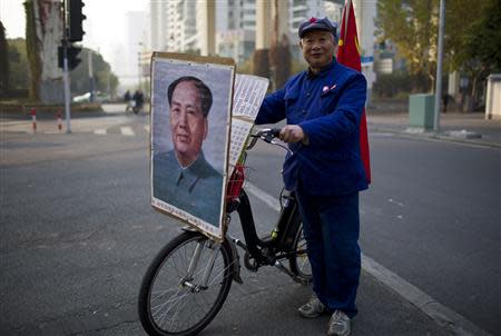 Qiu, a 65-year-old retired shipyard worker wearing a Red Army hat, poses for a photograph with his bicycle bearing a portrait of China's late Chairman Mao Zedong on a street in Shanghai, December 2, 2013. REUTERS/Aly Song