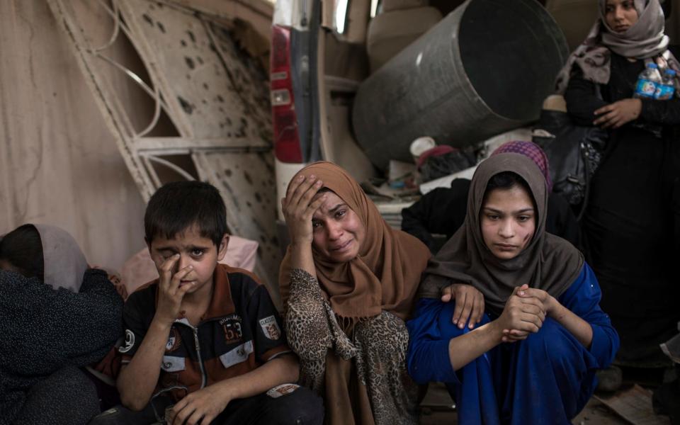 Fleeing Iraqi civilians sit inside a house as they wait to be taken out of the Old City during fighting between Iraqi forces and Islamic State militants in Mosul, Iraq - Credit: AP