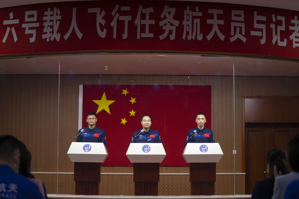 Chinese astronauts for the upcoming Shenzhou-16 mission, from left, Gui Haichao, Jing Haipeng, and Zhu Yangzhu stand behind glass during a meeting with the press at the Jiuquan Satellite Launch Center in northwest China on Monday, May 29, 2023. China's space program plans to land astronauts on the moon before 2030, a top official with the country's space program said Monday. (AP Photo/Mark Schiefelbein)