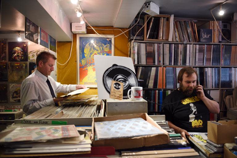 A customer peruses the vinyl for sale in the music shop Record Collector as employee Joe Blanchard (R) speaks to a customer on the phone ahead of Record Store Day in Sheffield, England on April 17, 2015