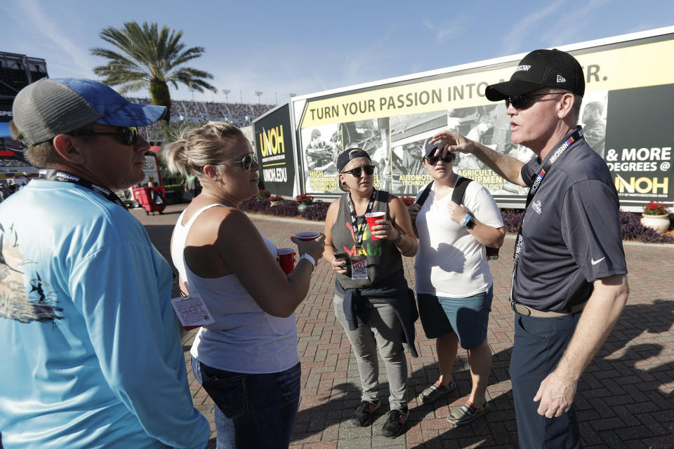 Eric Nyquist, right, a senior vice president and chief communications officer with NASCAR, greets fans in the infield and thanks them for returning for the resumption of the Daytona 500 auto race at Daytona International Speedway, Monday, Feb. 17, 2020, in Daytona Beach, Fla. Sunday's race was postponed because of rain. (AP Photo/John Raoux)