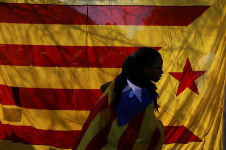 A woman wearing an Estelada (Catalan separatist flag) walks past another big Estelada during a gathering in support of the banned October 1st independence referendum in Barcelona, Spain, September 24, 2017. REUTERS/Susana Vera