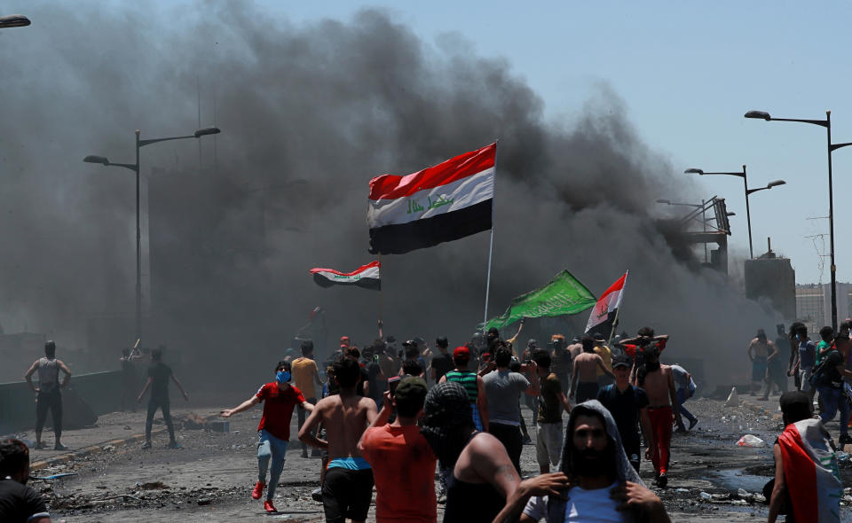 Anti-government protesters burn tires in front of barriers set up by security forces to close the Jumhuriyah Bridge leading to the Green Zone government area, during ongoing protests in Baghdad, Iraq, Sunday, May 10, 2020. Protesters were back on the streets three days after Mustafa al-Kadhimi was appointed as Iraq's new prime minister. (AP Photo/Hadi Mizban)