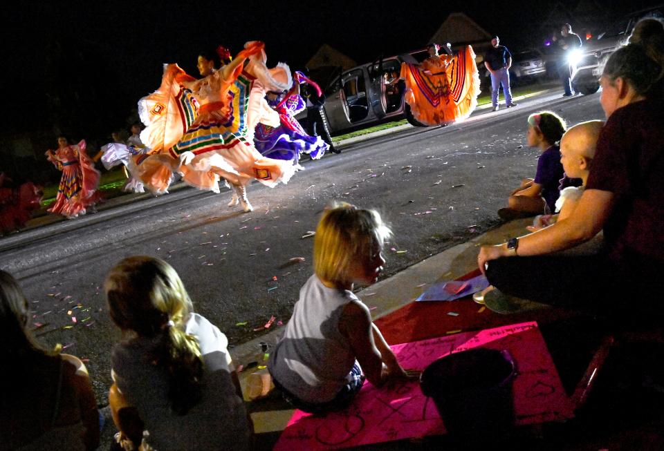 Sienna Molina sits in the lap of Britany Fullerton (right) as they watch the Ballet Folkloric de Alvaro Munoz perform in the street outside the Molina family home Tuesday. Hundreds rallied in south Abilene to show support for three-year-old Sienna in the wake of her terminal cancer prognosis days earlier.