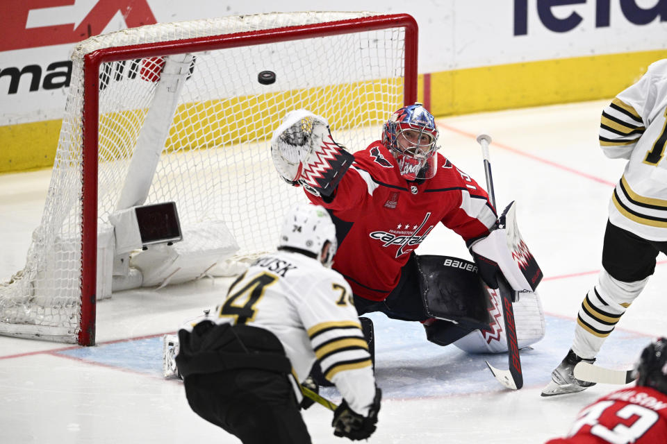 Washington Capitals goaltender Charlie Lindgren (79) reaches for the puck against Boston Bruins left wing Jake DeBrusk (74) during the third period of an NHL hockey game, Monday, April 15, 2024, in Washington. The Capitals won 2-0. (AP Photo/Nick Wass)