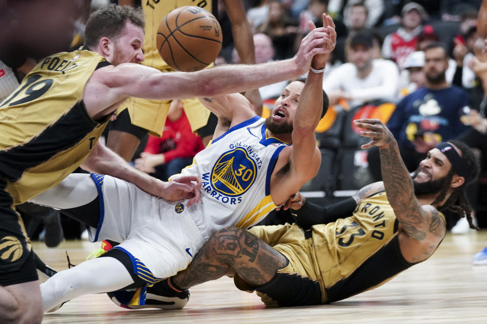 Golden State Warriors guard Stephen Curry (30) falls onto Toronto Raptors guard Gary Trent Jr. (33) during the first half of an NBA basketball game Friday, March 1, 2024, in Toronto. (Arlyn McAdorey/The Canadian Press via AP)