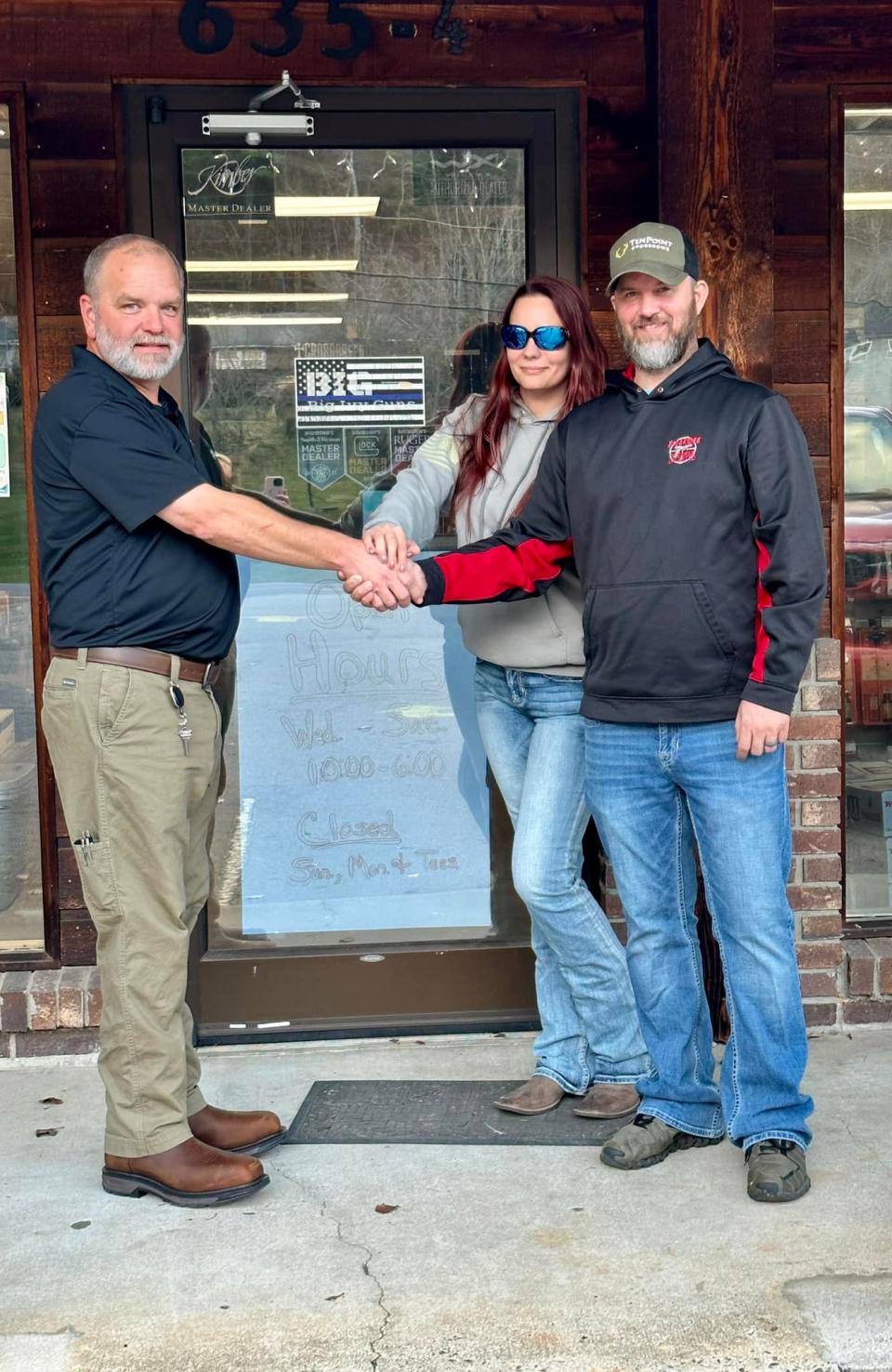 Big Ivy Guns owner Quincy Brock, left, shakes hands with Blueridge Firearms Unlimited owners Jerica and Jason Lawson to commemorate Blueridge Firearms Unlimited's acquisition of the Mars Hill gun store.