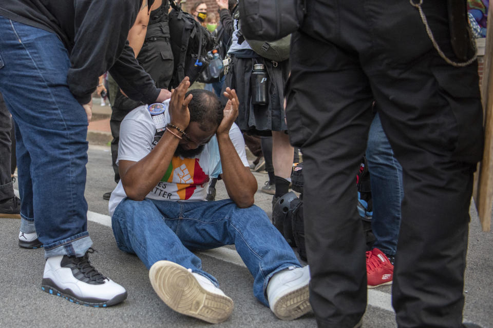 In this Sept. 25, 2020 photo, a man reacts after the Louisville Police Department fired flash-bang grenades into a crowd of protesters. Chief Robert Schroeder said during a news conference the police used the grenades to get the crowd's attention to provide direction on how to disperse. (Isabel Miller via AP)