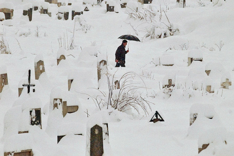 FILE - A man walking through Kosevo cemetery makes his way through deep snow, Wednesday morning, Dec. 13, 1995 in Sarajevo. Former award-winning Associated Press photographer John Gaps III, who documented everything from war zones to the NCAA College World Series during his career, was found dead at his home Monday, Oct. 17, 2022, in Des Moines, Iowa, his family confirmed Tuesday. He was 63. (AP Photo/John Gaps III, File)