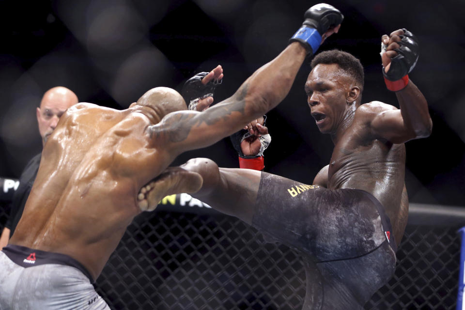 FILE- In this March 7, 2020, file photo, UFC middleweight champion Israel Adesanya, right, of Nigeria, kicks challenger Yoel Romero, of Cuba, during the second round of their UFC 248 fight at the T-Mobile Arena in Las Vegas. Israel Adesanya returns to the UFC cage this weekend to defend his middleweight title against Paulo Costa in the main event of UFC 253. (L.E. Baskow/Las Vegas Review-Journal via AP, File)