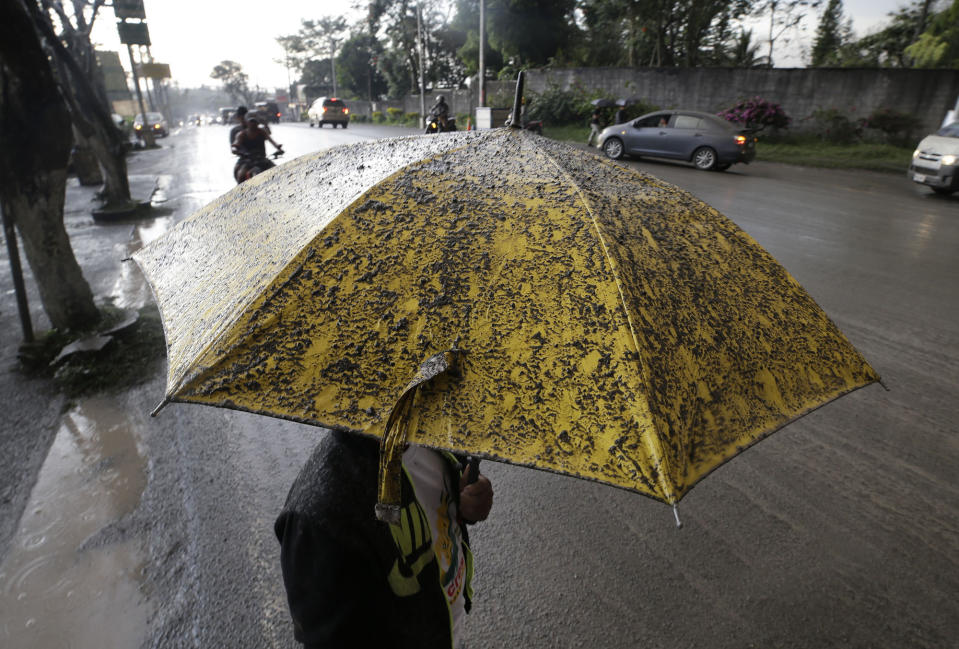 Un hombre utiliza un paraguas para cubrirse de la caída de ceniza luego de que el volcán Taal expulsó una columna de vapor y cenizas el domingo 12 de enero de 2020, en Tagaytay, Filipinas. (AP Foto/Aaron Favila)