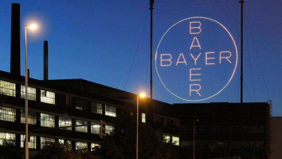 Das Logo der Bayer AG hängt beleuchtet über der Hauptzentrale in Leverkusen.