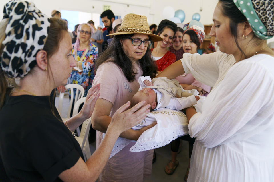 Samantha Sandovski, right, places her newborn son, Israel, on a pillow held by her mother, Ann Kravitz, during a brit milah, a Jewish circumcision ceremony, in the mixed Arab-Jewish town of Lod, central Israel, Tuesday, May 25, 2021. The Sandovski's, part of the Torah Nucleus community, left Lod during the recent clashes between Arabs, Jews and police, and returned uncertain if they should remain. "Suddenly it changed," said Sandovski of her relations with her Arab neighbors. "We don't know who was against us and I am scared to trust them now. Everything is complicated now." (AP Photo/David Goldman)