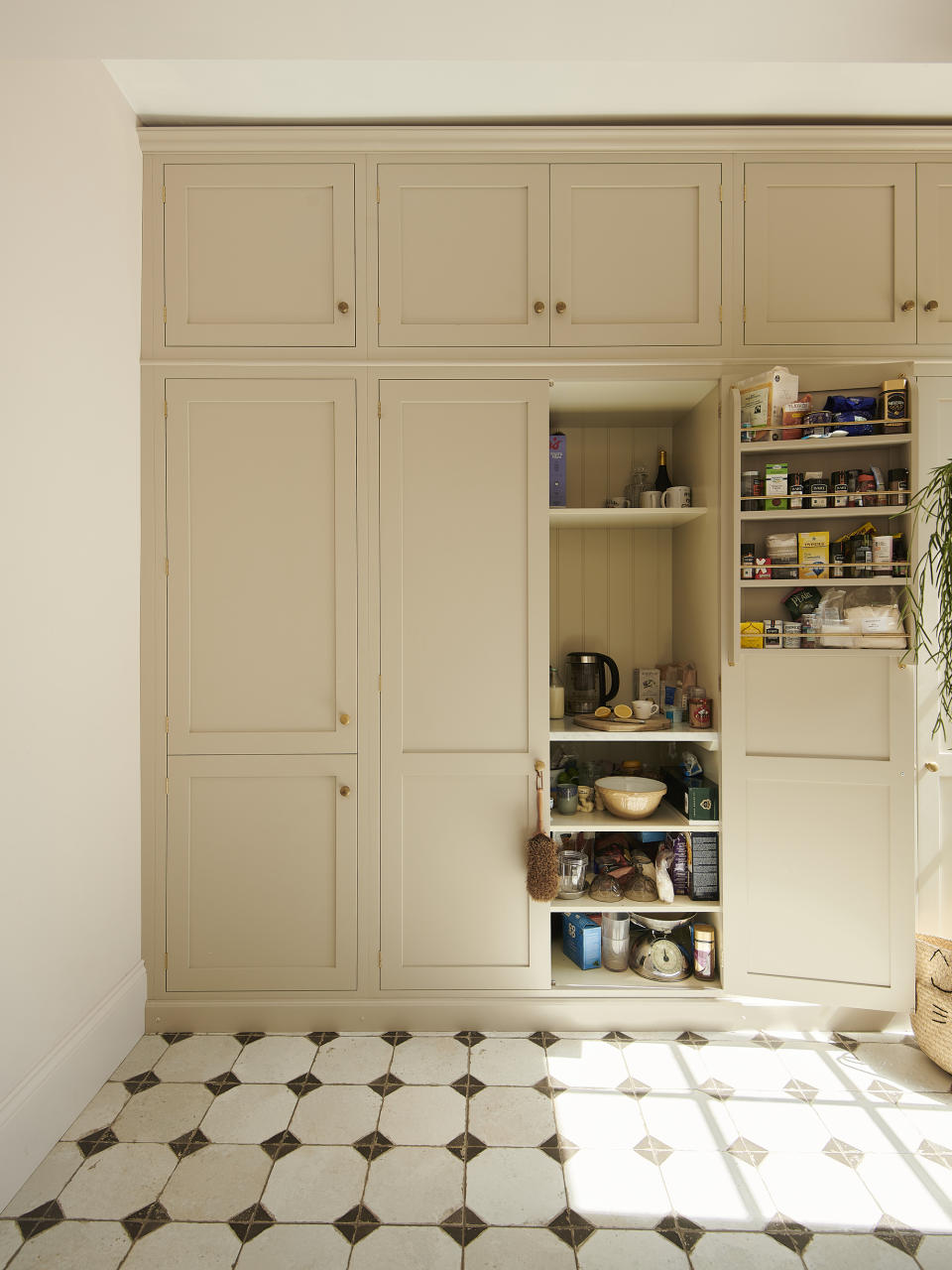 Cream coloured shaker style kitchen cabinets which open onto an appliance garage with door shelving racks
