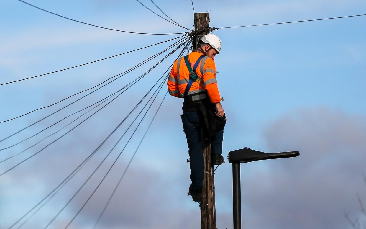 An Openreach engineer carries out maintenance work at the top of a telegraph pole