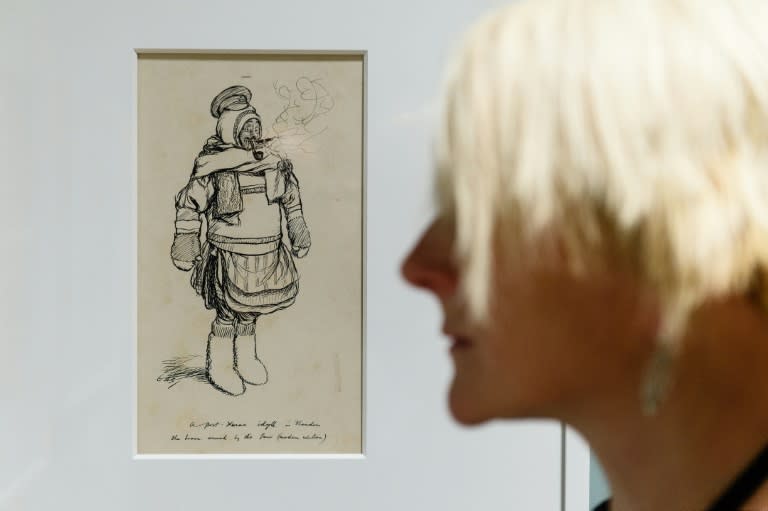 A gallery assistant poses in front of a drawing by British illustrator E.H. Shepard entitled, "Gallant attempt by a member of the British Expeditionary Force to do justice to all his New Years' gifts"