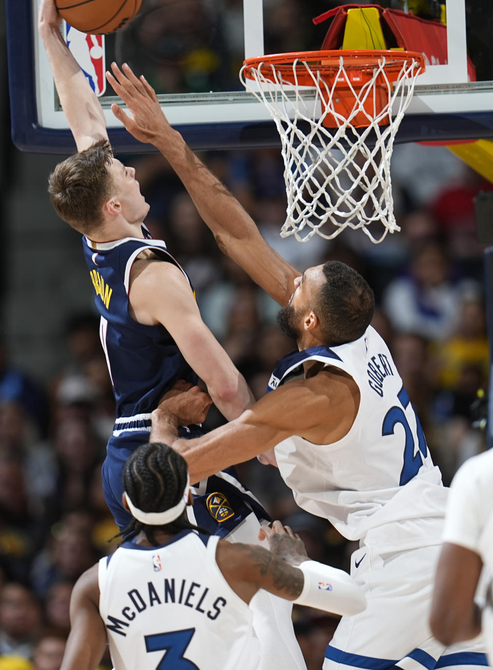 Denver Nuggets guard Christian Braun, left, drives to the basket for a dunk as Minnesota Timberwolves center Rudy Gobert, right, and forward Jaden McDaniels, front, defend during the second half of an NBA basketball game Wednesday, April 10, 2024, in Denver. (AP Photo/David Zalubowski)