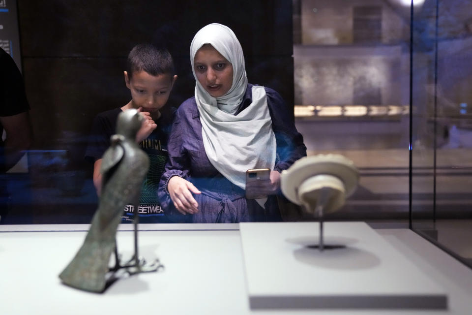 A woman with her son looks to an object at Islamic Art Museum in Doha, in Doha, Qatar, Wednesday, Dec. 7, 2022. (AP Photo/Jorge Saenz)