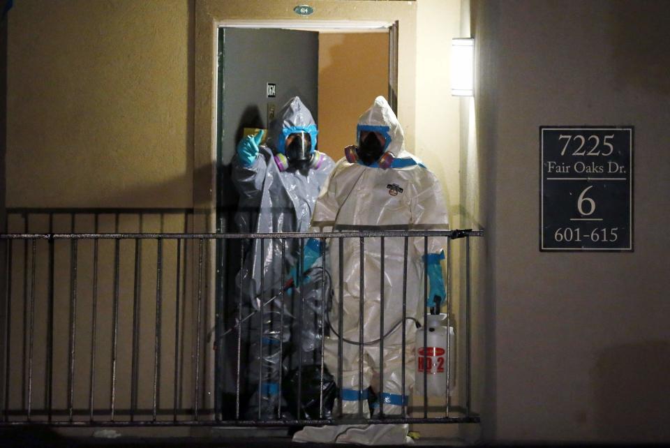 Workers in hazardous material suits step out of an apartment unit where a man diagnosed with the Ebola virus was staying in Dallas, Texas, October 5, 2014. (REUTERS/Jim Young)