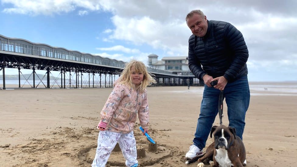 Holidaymakers on beach at Weston, a young girl with her dad and dog