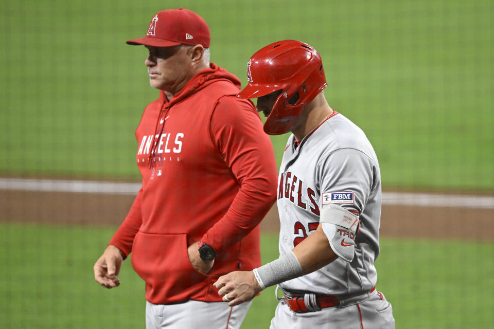 Los Angeles Angels' Mike Trout (27) walks next to manager Phil Nevin as he leaves the game during the eighth inning of a baseball game against the San Diego Padres Monday, July 3, 2023, in San Diego. (AP Photo/Denis Poroy)