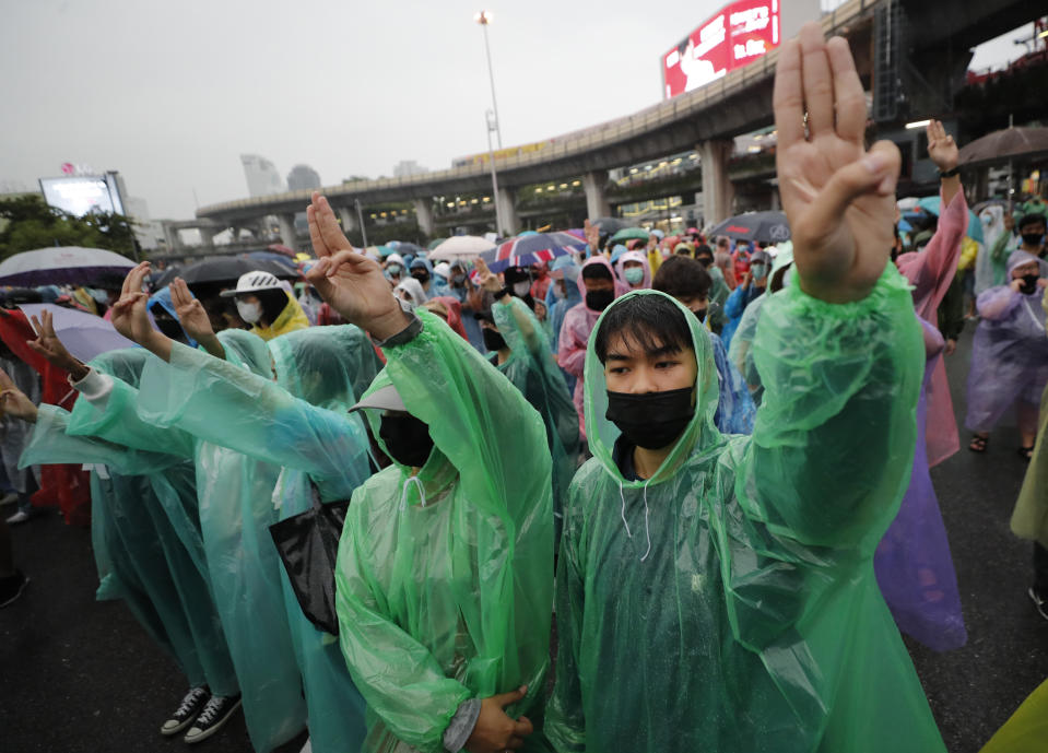 Pro-democracy protesters flash a three-fingered salute during rain at an anti-government protest at Victory Monument during a protest in Bangkok, Thailand, Sunday, Oct. 18, 2020. Thai police on Sunday declined to say whether they were taking a softer approach toward student anti-government demonstrations, after several mass rallies attracting thousands of protesters ended peacefully in Bangkok on Saturday. (AP Photo/Sakchai Lalit)