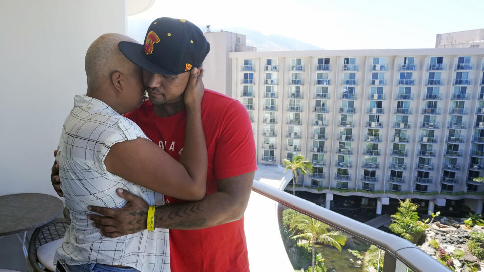 JP Mayoga, right, a chef at the Westin Maui, Kaanapali, and his wife, Makalea Ahhee, hug on their balcony at the hotel and resort, Sunday, Aug. 13, 2023, near Lahaina, Hawaii. About 200 employees are living there with their families. Officials urge tourists to avoid traveling to Maui as many hotels prepare to house evacuees and first responders on the island where a wildfire demolished a historic town and killed dozens of people. (AP Photo/Rick Bowmer)