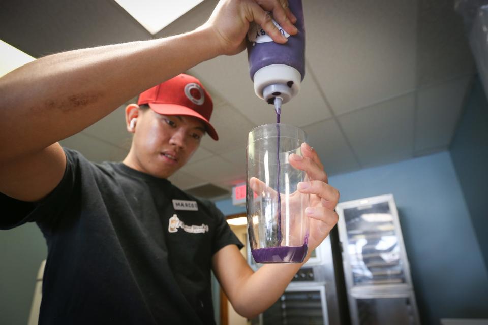 Marco Bautista fills a cup full of ube-flavored sauce at Filipino Market's Boba & Bakery on Friday, Aug. 11, 2023.