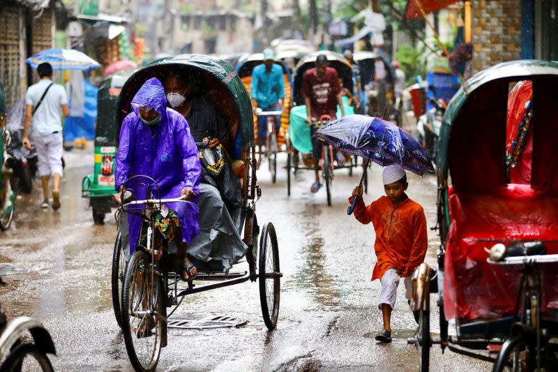 Commuters are seen on a street during rain amid the coronavirus disease (COVID-19) pandemic, in Dhaka