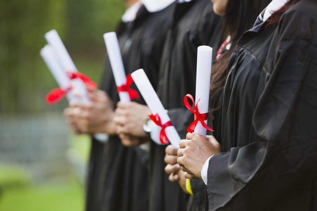 School graduates hold their diplomas