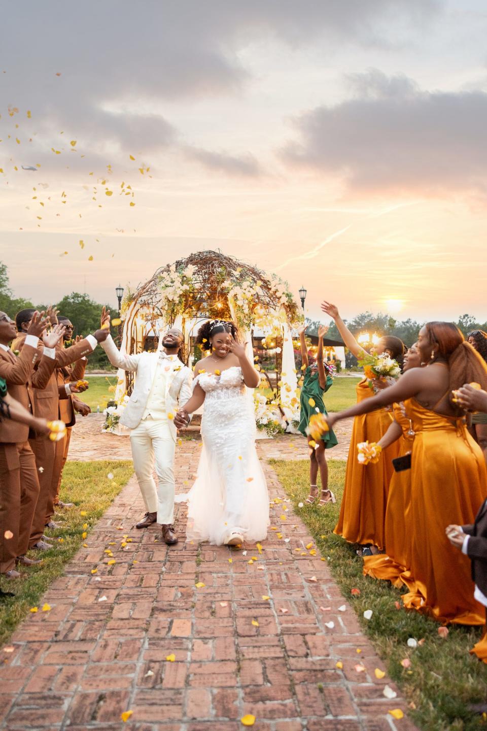 A bride and groom are covered in flower petals as they leave their wedding.