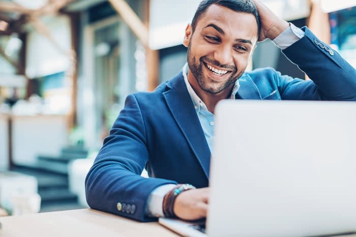 Smiling person looking at a laptop in an office.