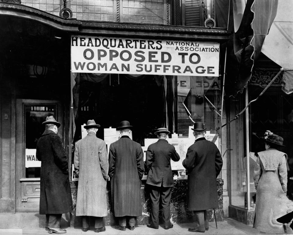 In this circa 1911 photo made available by the Library of Congress, men look at materials posted in the window of the National Anti-Suffrage Association headquarters in the United States. (Harris & Ewing/Library of Congress via AP)