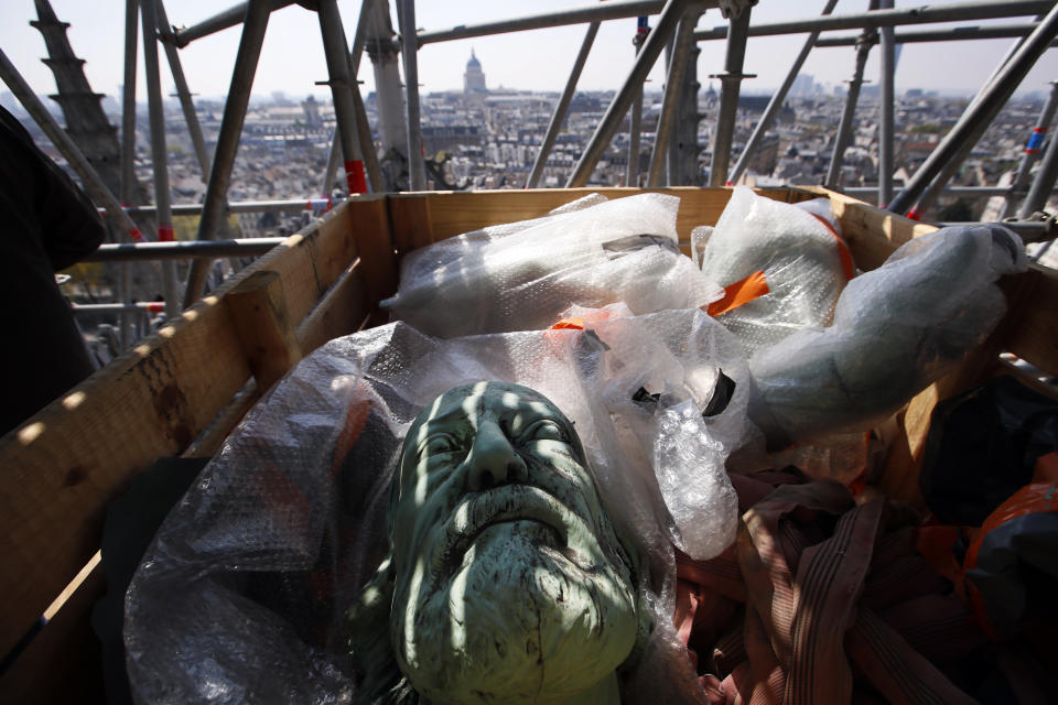 The head of a religious statue representing St. Thomas atop Paris' Notre Dame Cathedral is loaded in a box prior to descend to earth for the first time in over a century as part of a restoration, in Paris Thursday, April 11, 2019. The 16 greenish-gray copper statues, which represent the twelve apostles and four evangelists, are lowered by a 100 meter (105 yard) crane onto a truck to be taken for restoration in southwestern France. (AP Photo/Francois Mori)