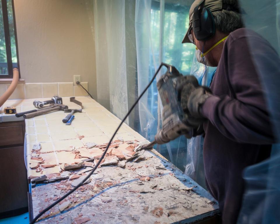 A worker uses a power tool to renovate countertops. 