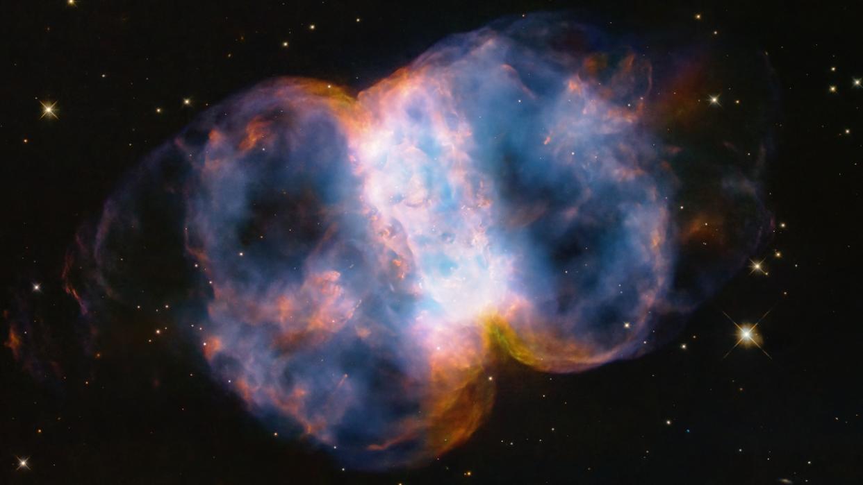  An opaline view of a nebula in space in the shape of a puffy dumbbell. 