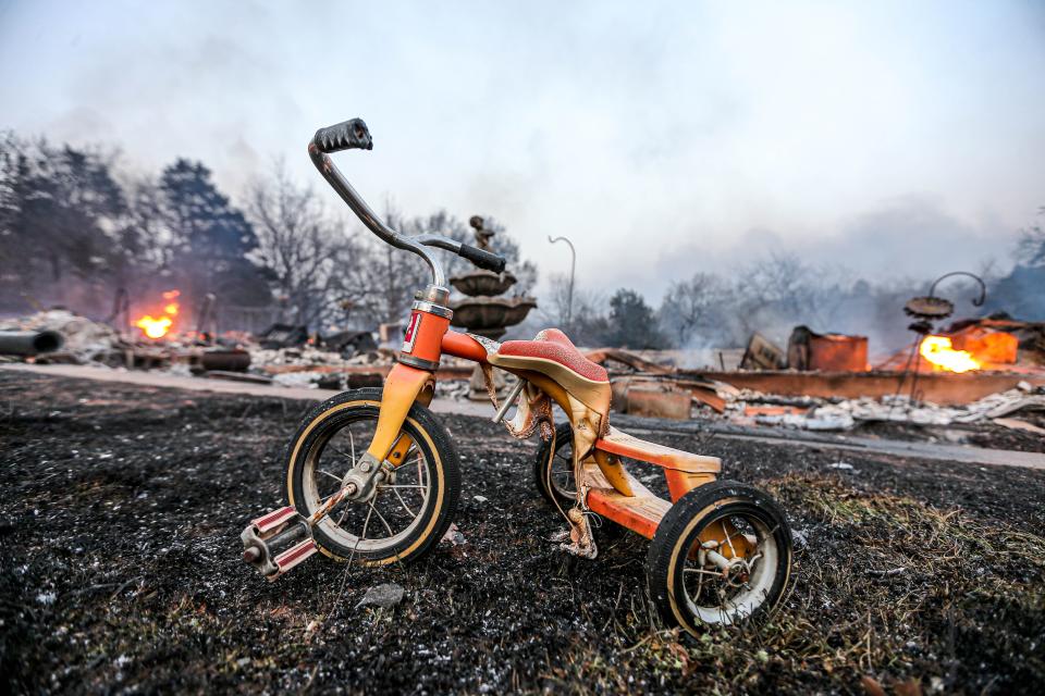 A melted tricycle sits Friday in front of the burned home of Margie Clark in the Guthrie area.