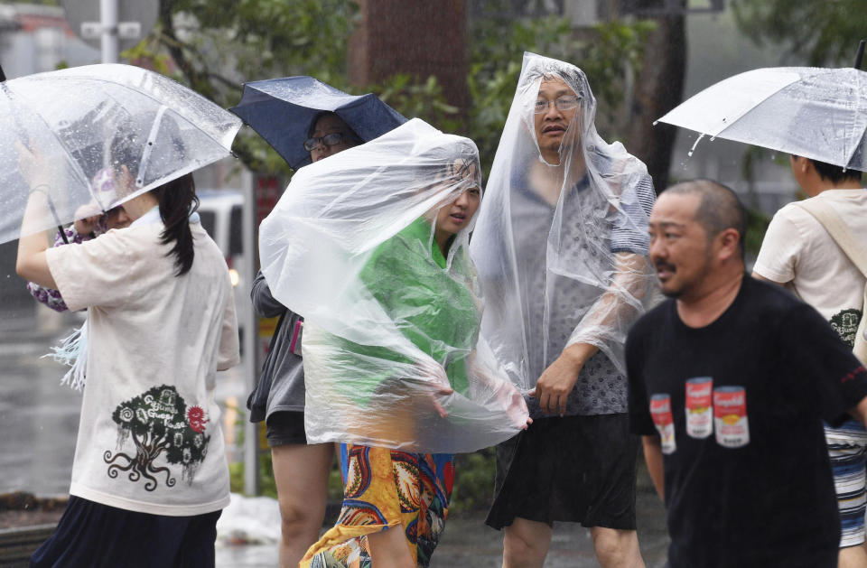 People walk in a strong wind as a typhoon approaches in Naha, Okinawa prefecture, southern Japan Saturday, Sept. 29, 2018. (Ryosuke Uematsu/Kyodo News via AP)