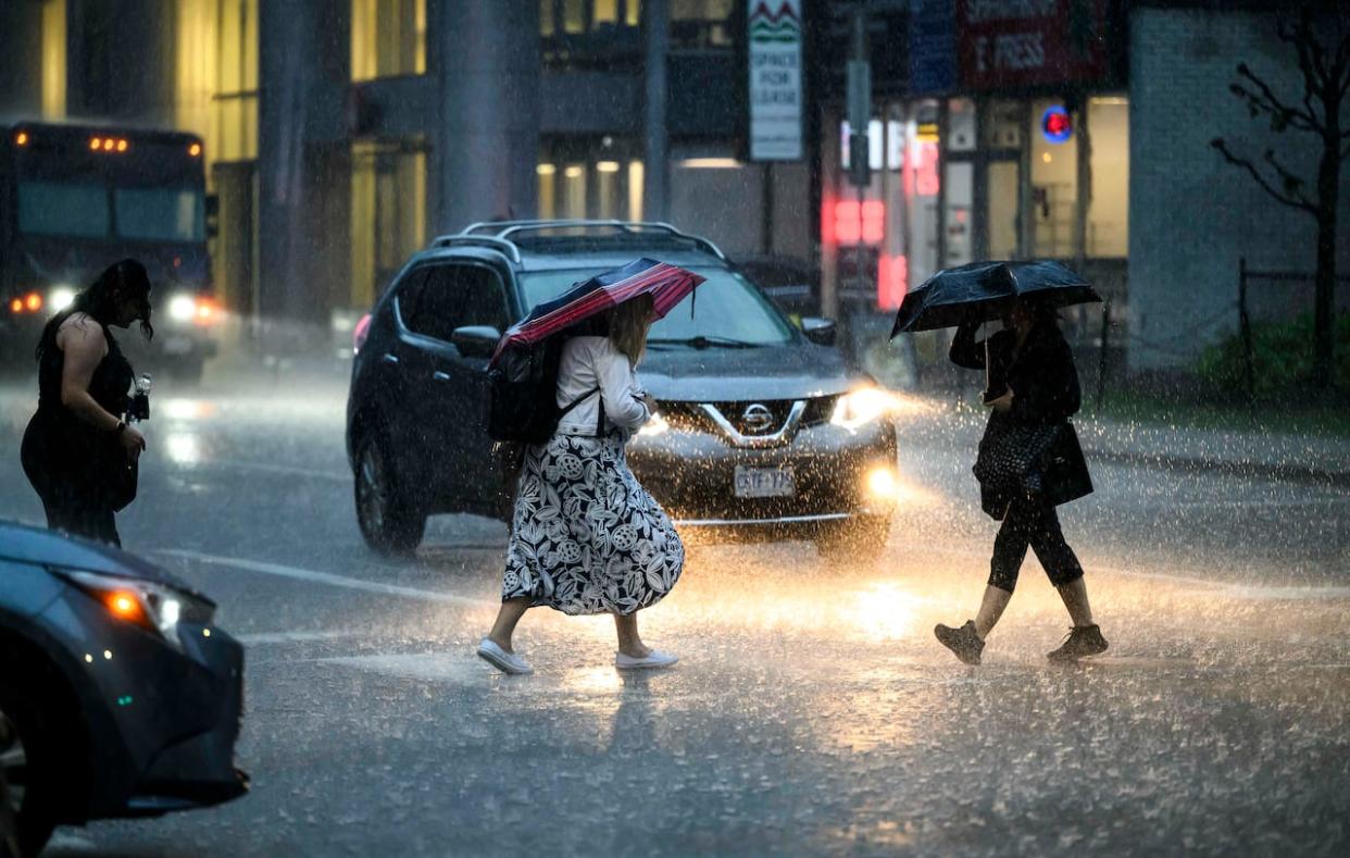 Pedestrians endure a heavy downpour in downtown Ottawa last month. On Monday, Environment Canada warned the Ottawa-Gatineau area along with other parts of Ontario could experience heavy downpours associated with Hurricane Beryl later this week. (The Canadian Press/Justin Tang - image credit)